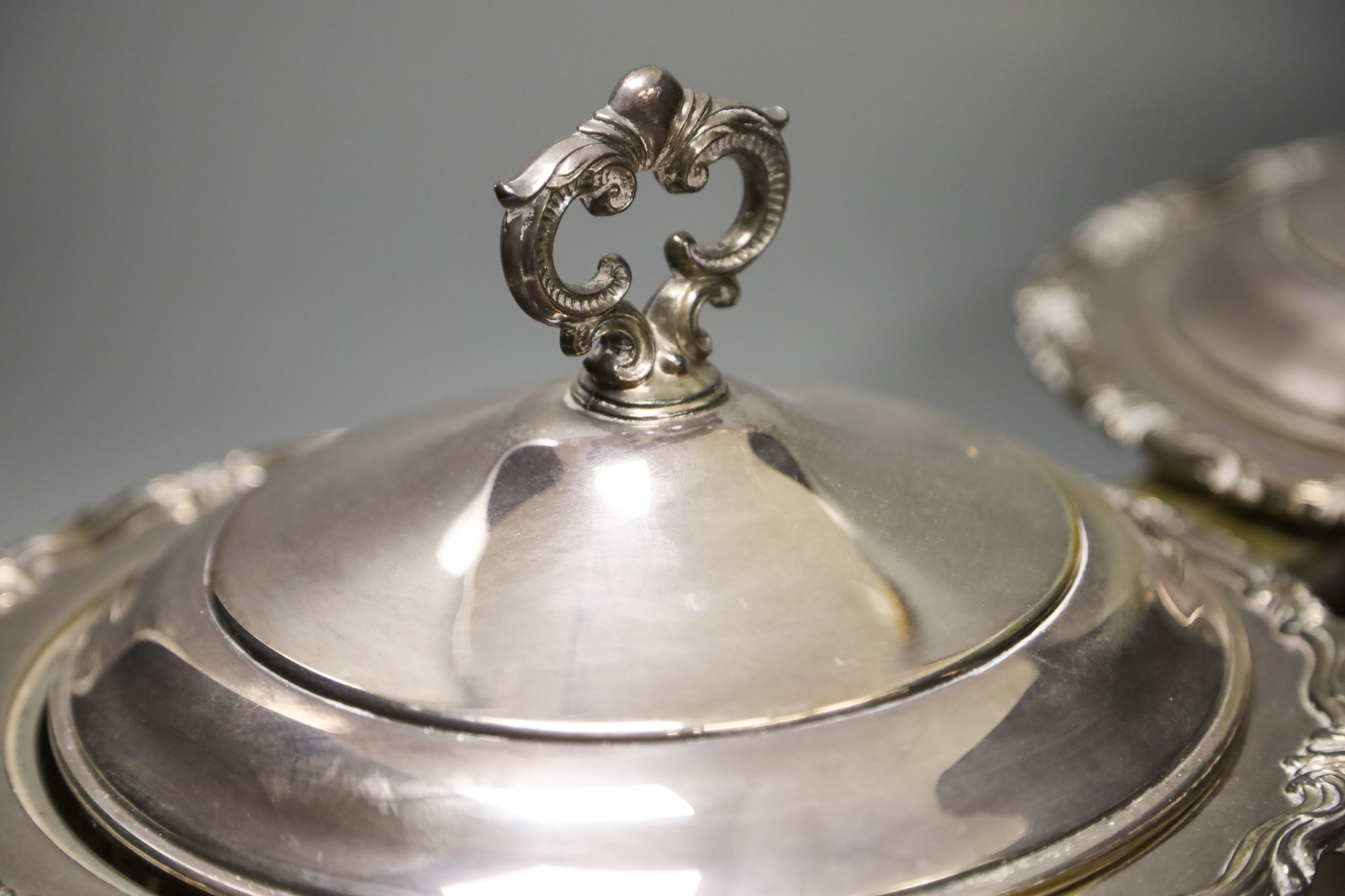 A pair of cast plated shaped oval entree dishes and covers and pair of linked cast plated breakfast braziers and covers, with turned wood handles